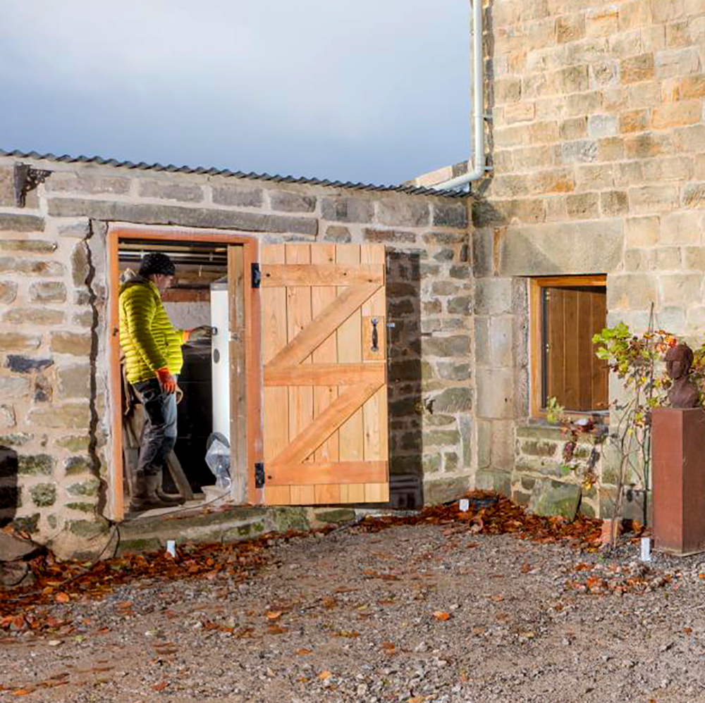 An engineer adjusts controls on a new carbon-friendly technology in a historic stone-built outbuilding. 