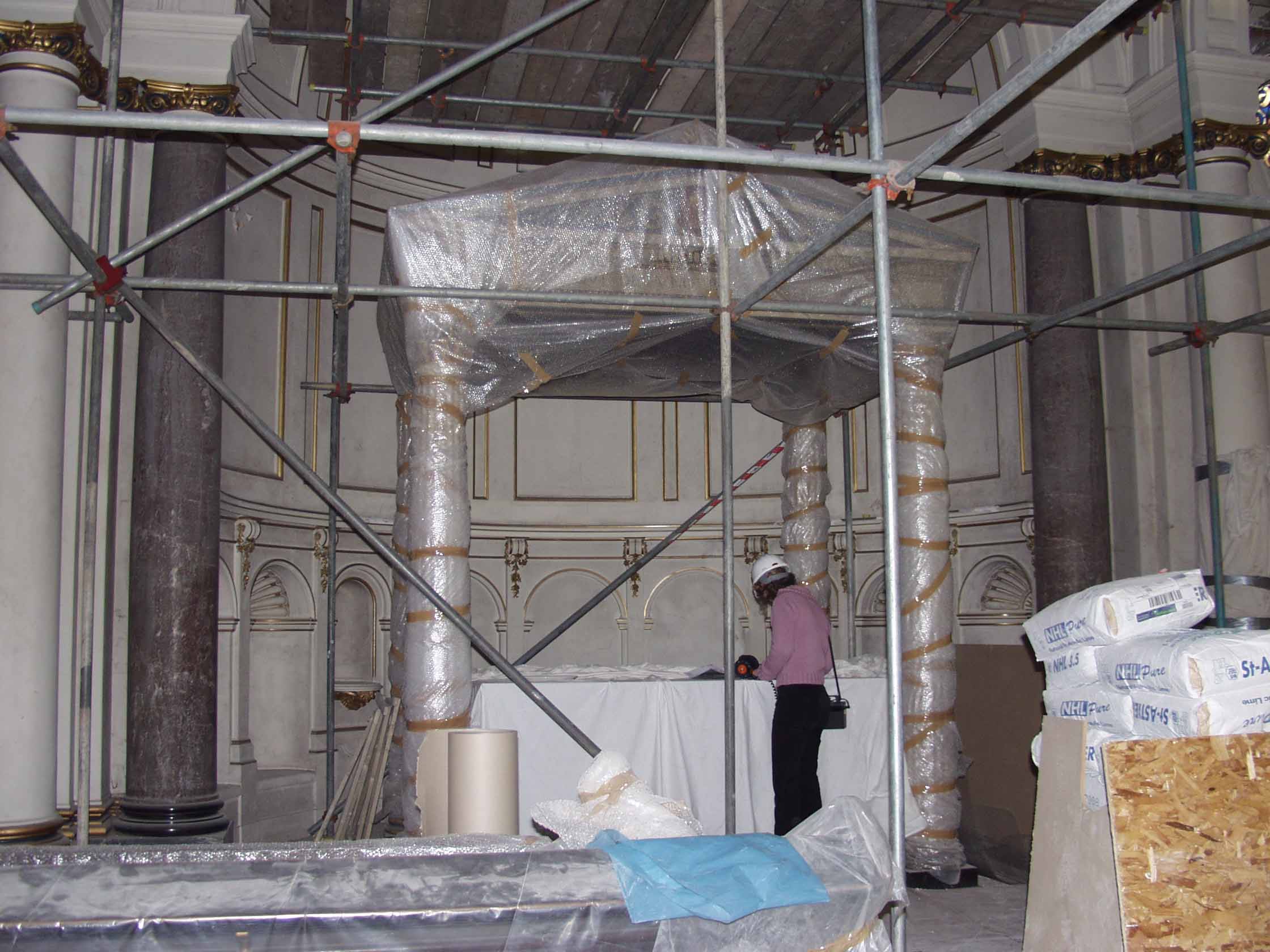A baldaquin covered in bubble-wrap, flanked by two columns and surrounded by scaffolding.