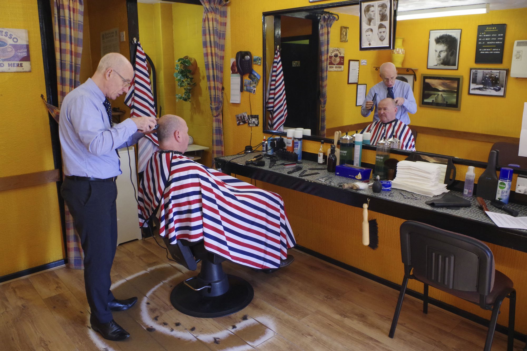 A man getting his hair cut by a barbe.