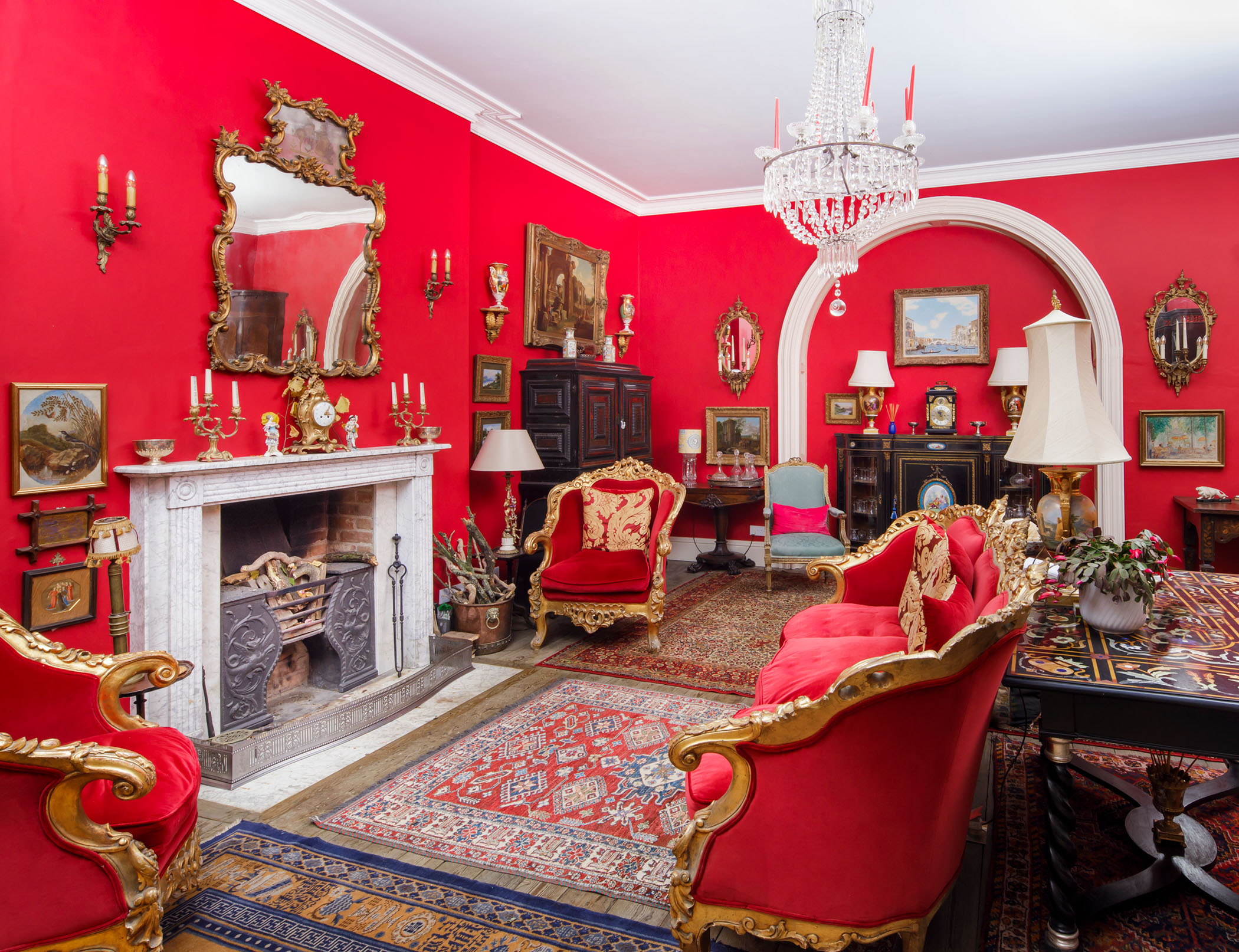 Interview view of a mostly red Regency-style drawing room within a manor house