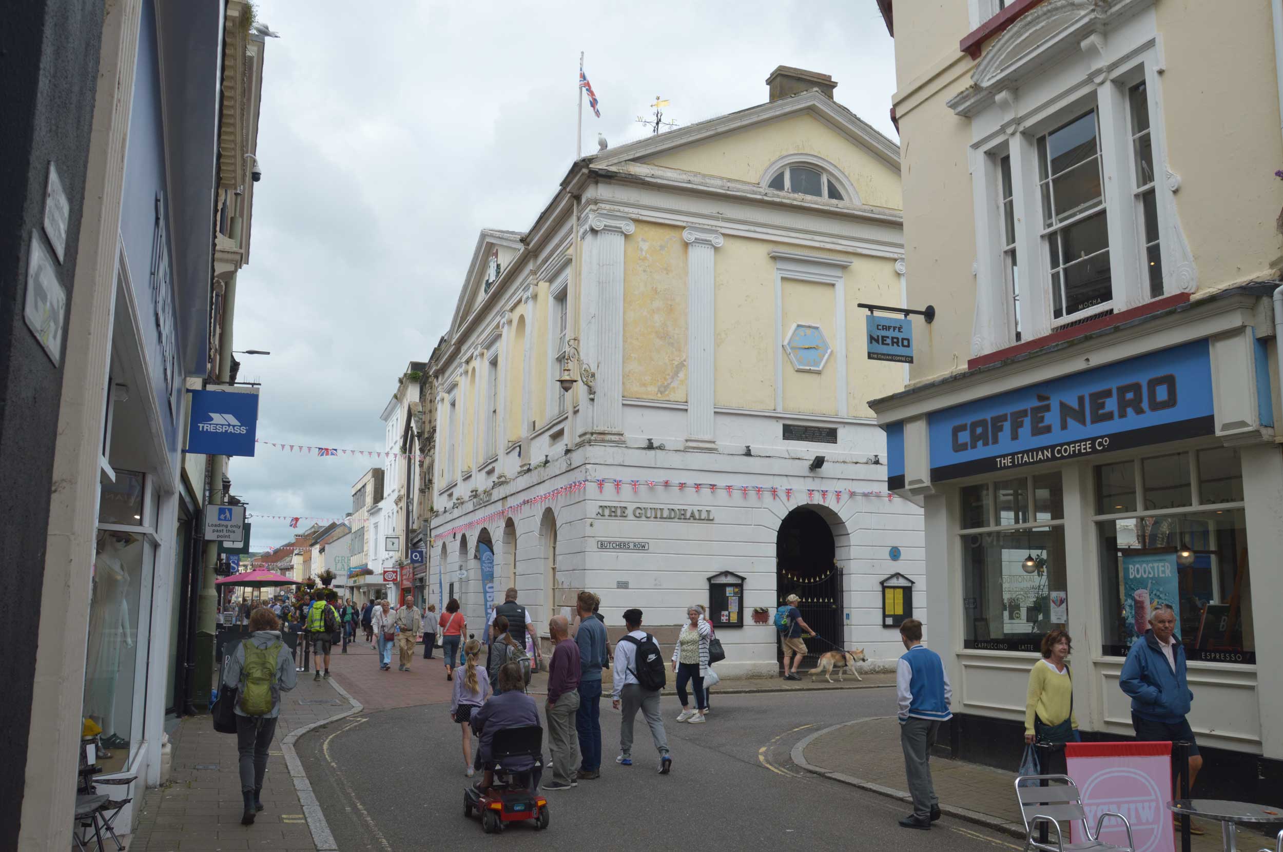A photograph of a High Street with a neoClassical building on the corner.