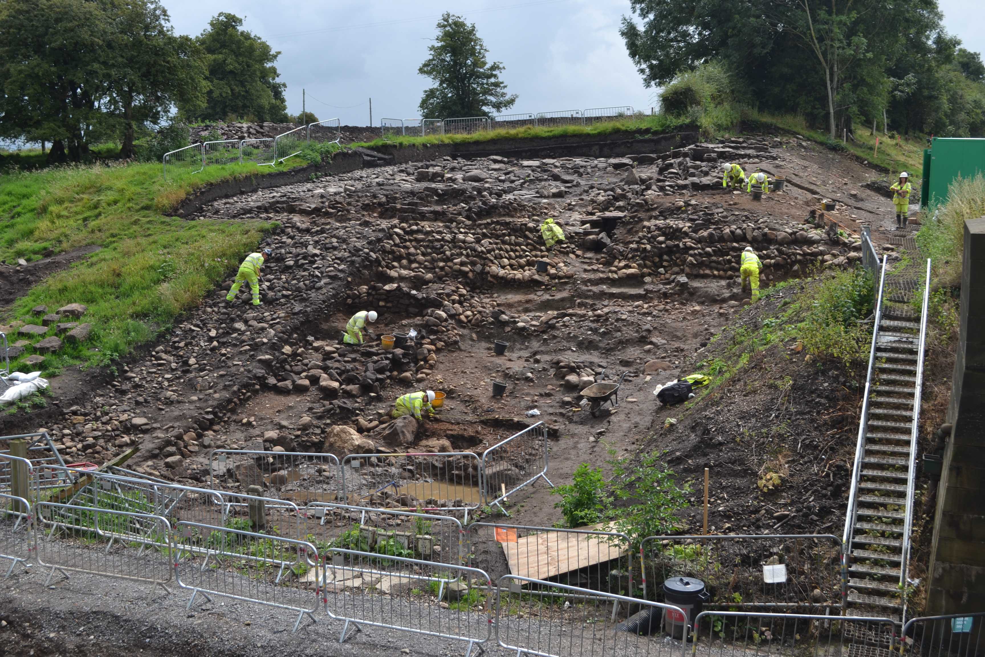 Image of archaeologists excavating Roman revetments, built to protect the river shore from erosion. This excavation was carried out in 2014, East of A1 on the south side of the River Swale near Catterick. 