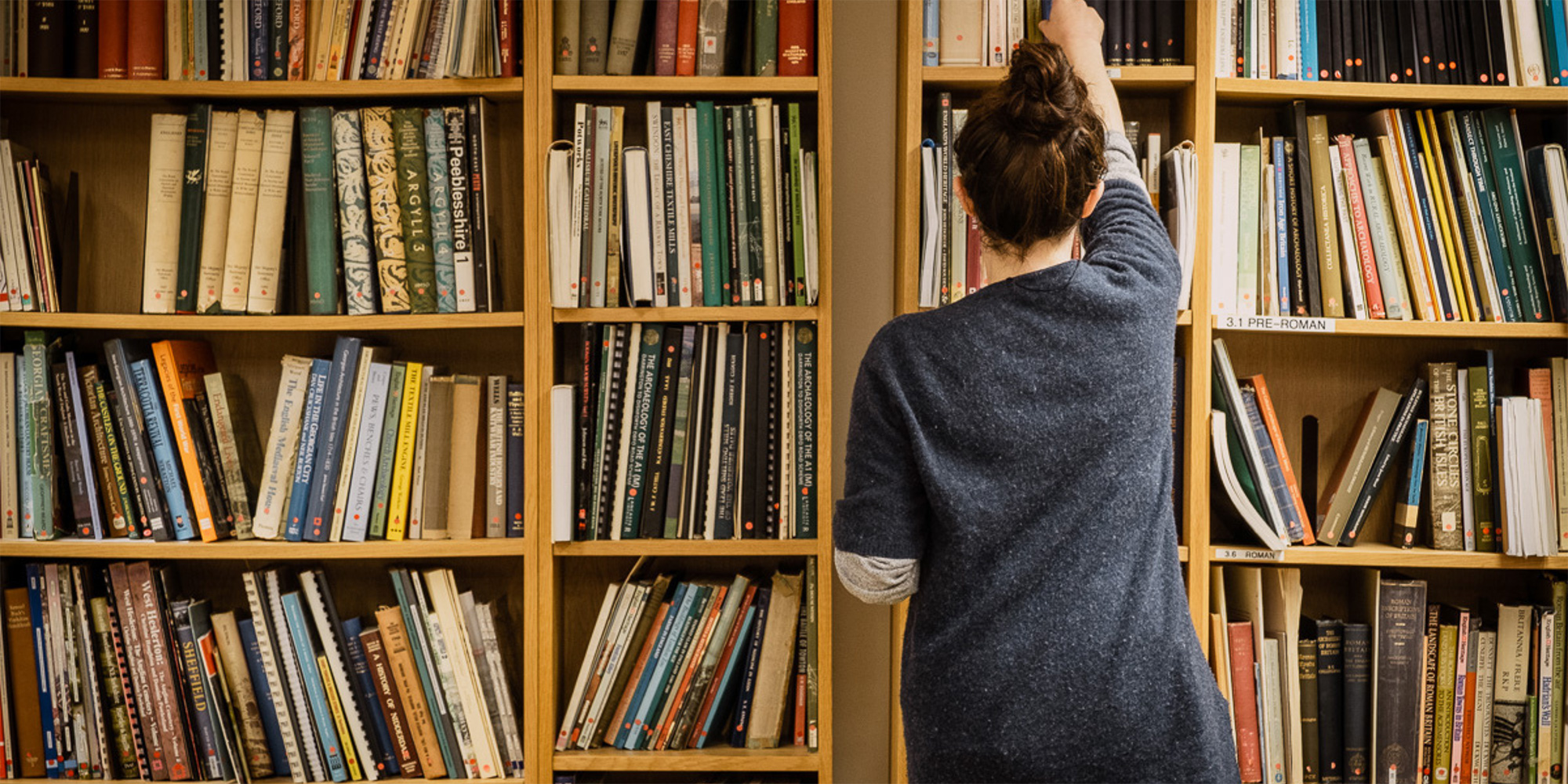 A librarian stacks books on a shelf.